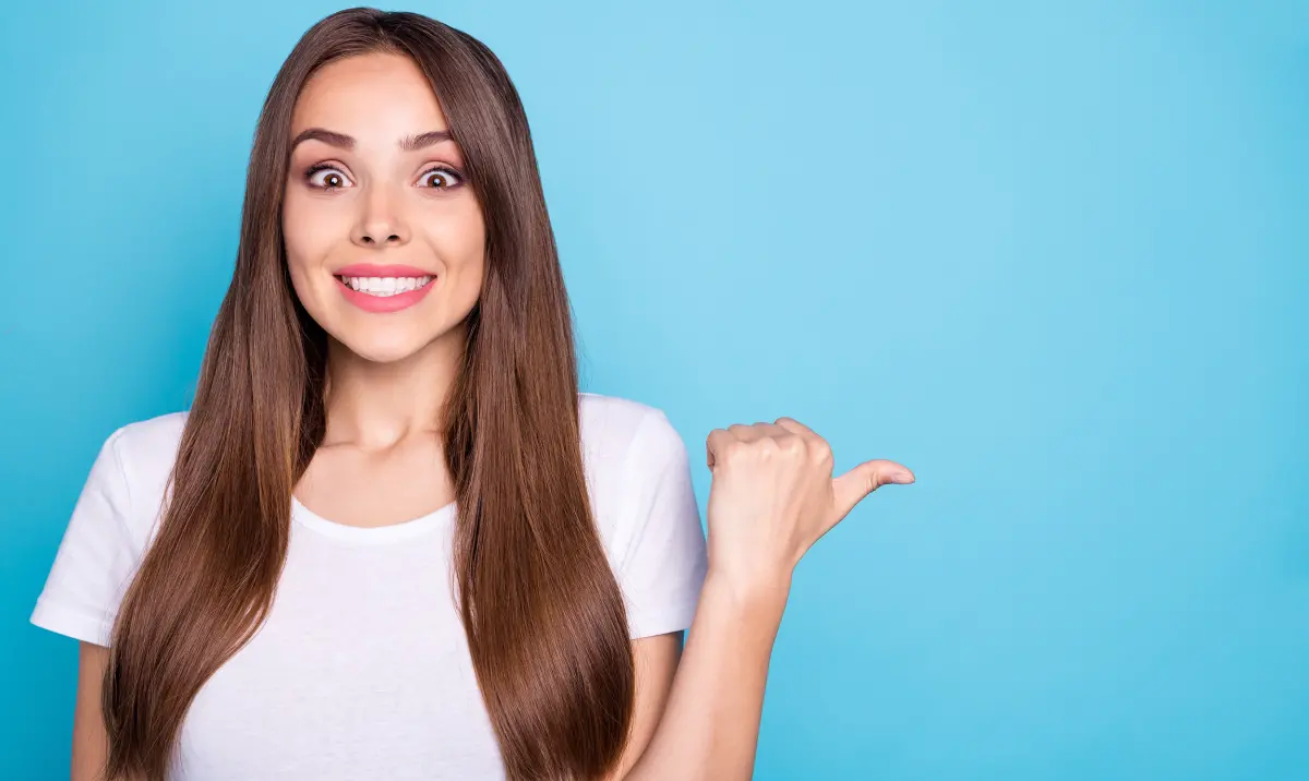 Jeune femme montrant quelque chose avec son pouce