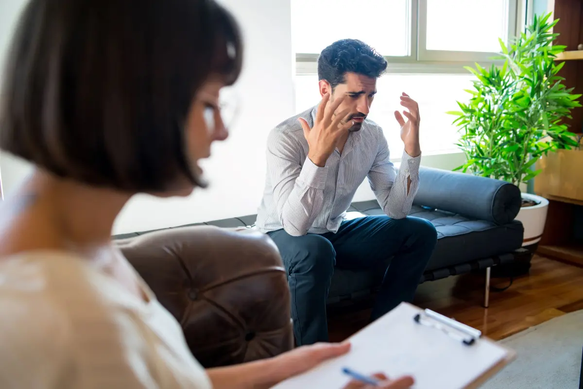 Homme assis sur un canapé parlant à une psychologue