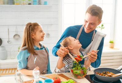 Un père avec ses deux filles préparant le repas