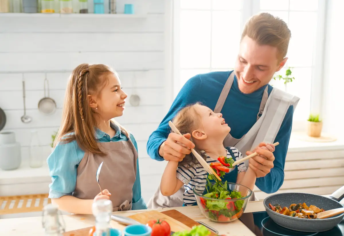 Un père avec ses deux filles préparant le repas