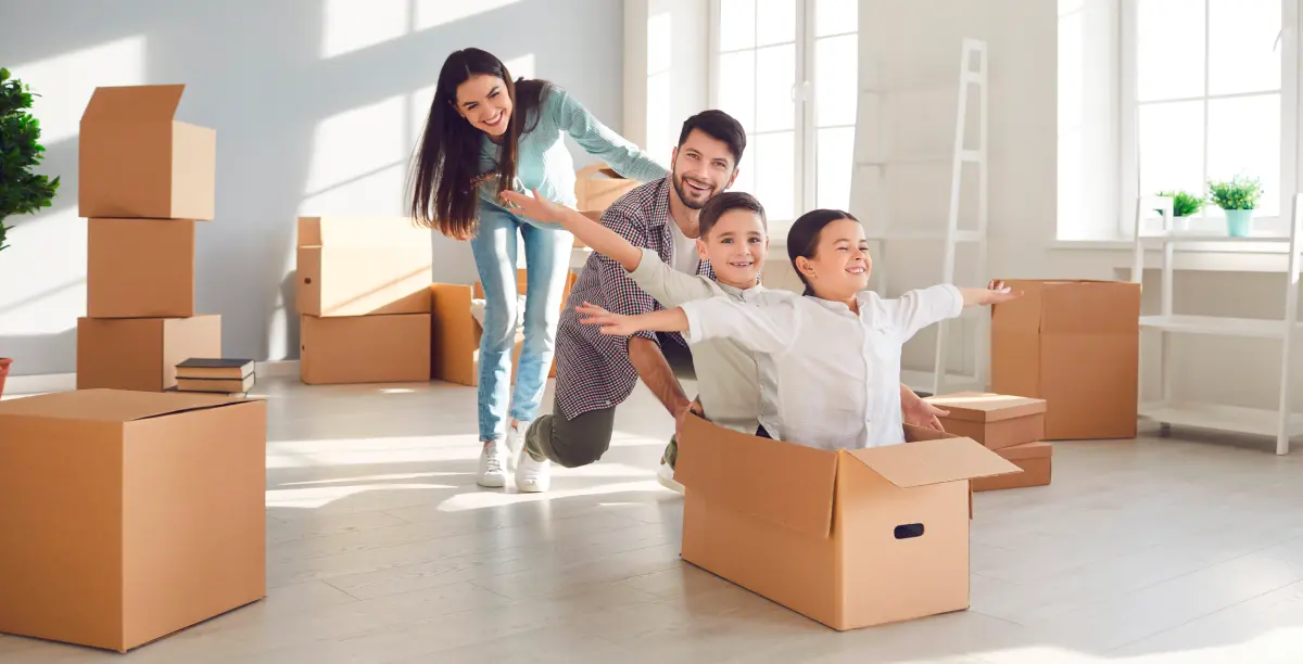 couple avec deux enfants s'amusant avec des cartons de déménagement