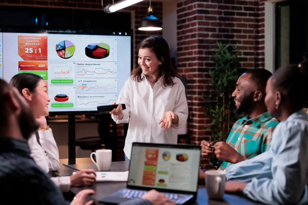 Femme souriante présentant des analyses d'affaires à une équipe heureuse dans un bureau moderne