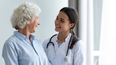 Une jeune femme médecin avec stéthoscope souriant à une femme âgée