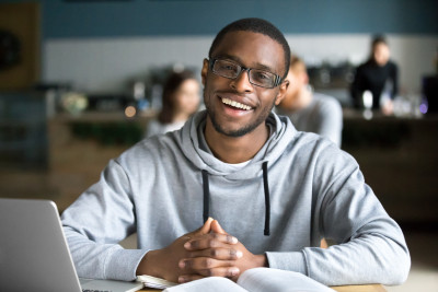 un etudiant qui sourit devant un ordinateur
