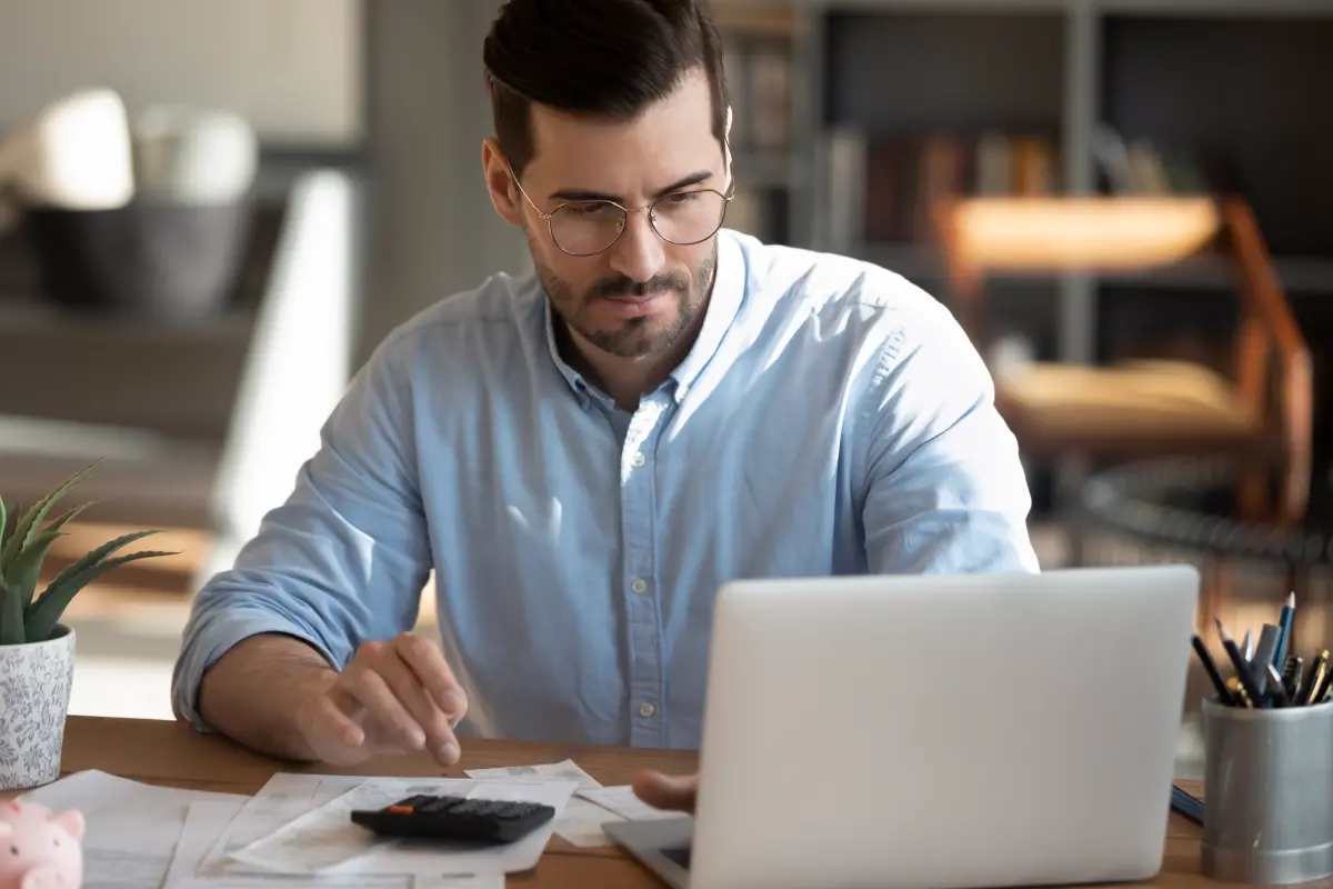 jeune homme fait des calcul devant son ordinateur
