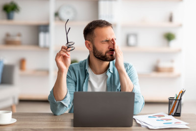 homme fatigué devant son écran se frotte les yeux