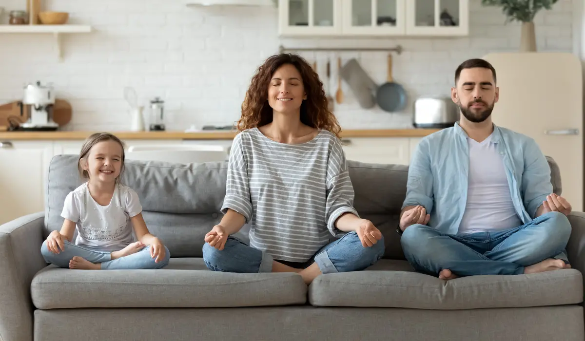 Famille assise sur un canapé faisant une séance de yoga
