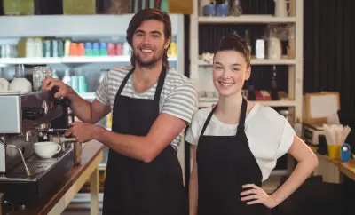 Deux jeunes serveurs souriants devant un percolateur