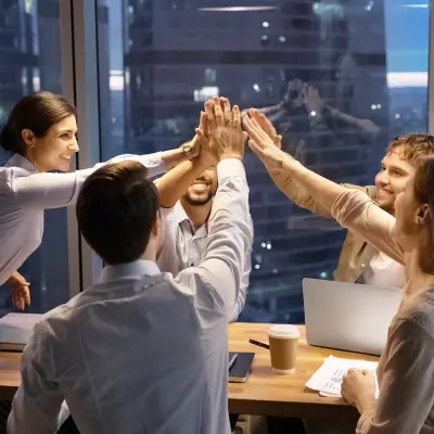 5 salariés fêtent leur succès autour d'un bureau dans un building