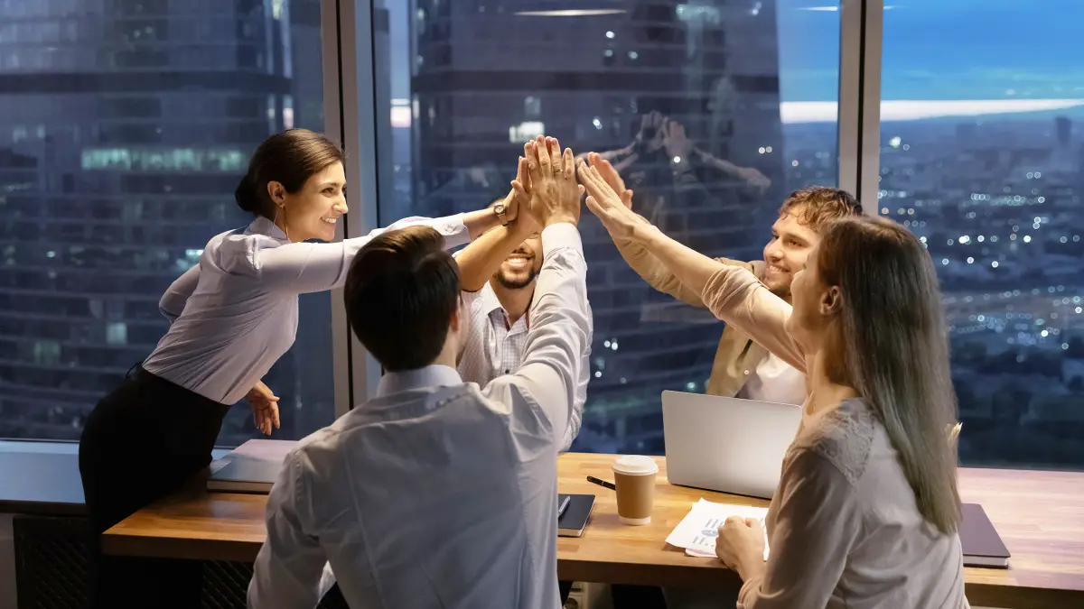 5 salariés fêtent leur succès autour d'un bureau dans un building
