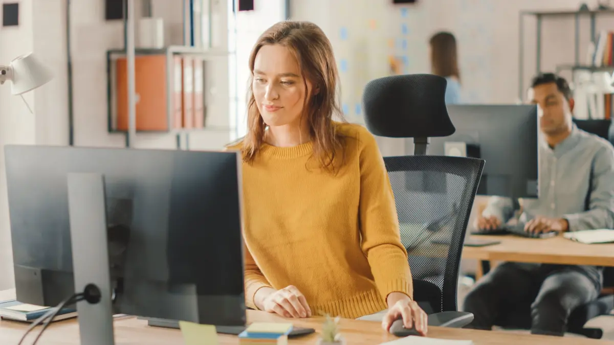 Femme avec un pull jaune devant son ordinateur