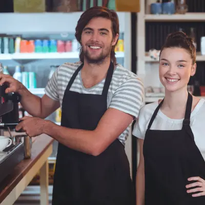 Deux jeunes serveurs souriants devant un percolateur